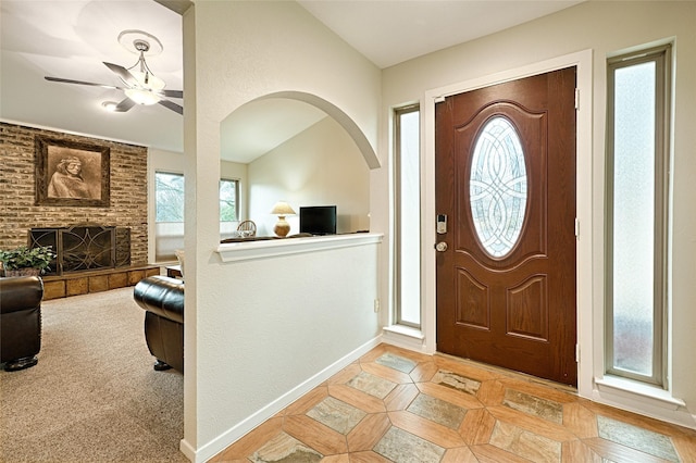 foyer featuring a fireplace, baseboards, vaulted ceiling, and a wealth of natural light