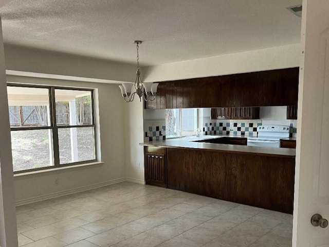 kitchen featuring pendant lighting, white range with electric cooktop, dark brown cabinets, a notable chandelier, and decorative backsplash