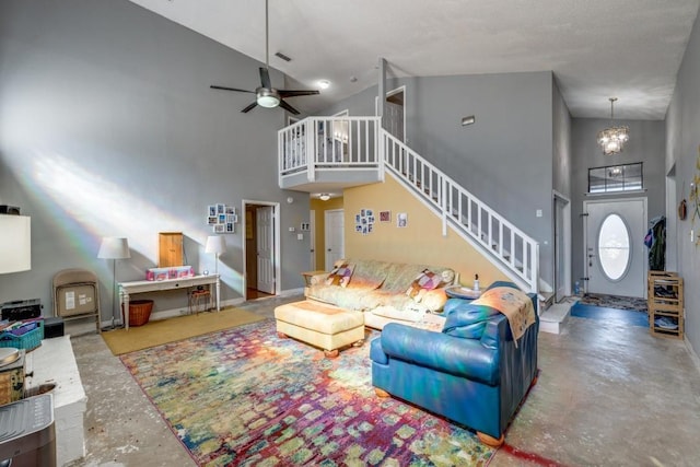 living room featuring concrete flooring, ceiling fan with notable chandelier, and high vaulted ceiling