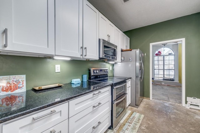 kitchen featuring dark stone countertops, appliances with stainless steel finishes, and white cabinets