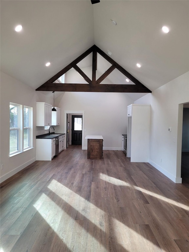 unfurnished living room featuring high vaulted ceiling, sink, and hardwood / wood-style floors