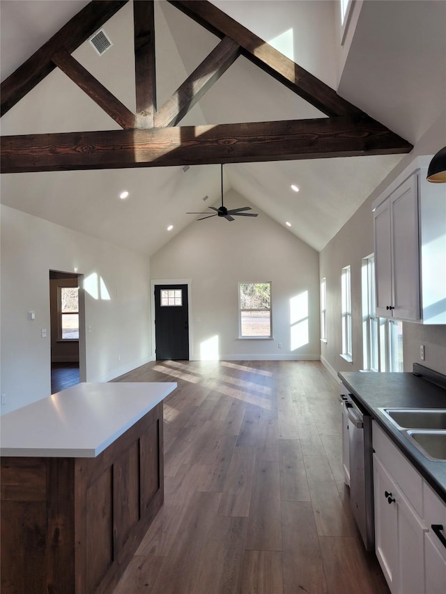 kitchen with hardwood / wood-style floors, a center island, white cabinets, stainless steel dishwasher, and beamed ceiling