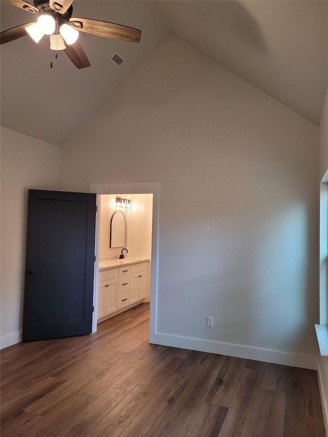 unfurnished bedroom with ensuite bathroom, dark wood-type flooring, ceiling fan, and high vaulted ceiling