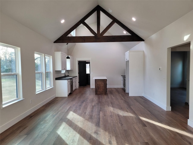 unfurnished living room with sink, hardwood / wood-style floors, and high vaulted ceiling