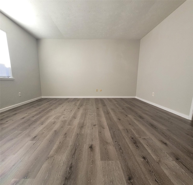 unfurnished room featuring dark hardwood / wood-style flooring and a textured ceiling