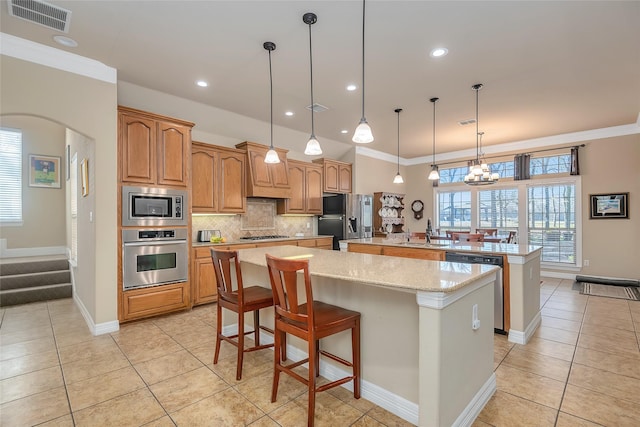 kitchen with sink, decorative light fixtures, a center island, appliances with stainless steel finishes, and a kitchen breakfast bar