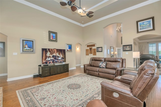 living room featuring crown molding, light hardwood / wood-style floors, ceiling fan, and a high ceiling