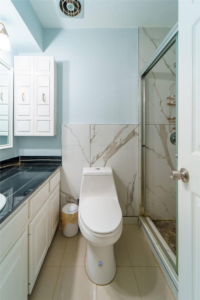 bathroom featuring tile patterned floors, a shower with door, and tile walls