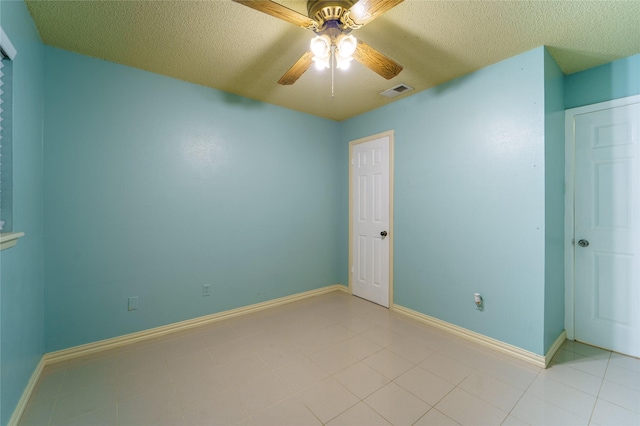 empty room featuring a textured ceiling, ceiling fan, and light tile patterned flooring