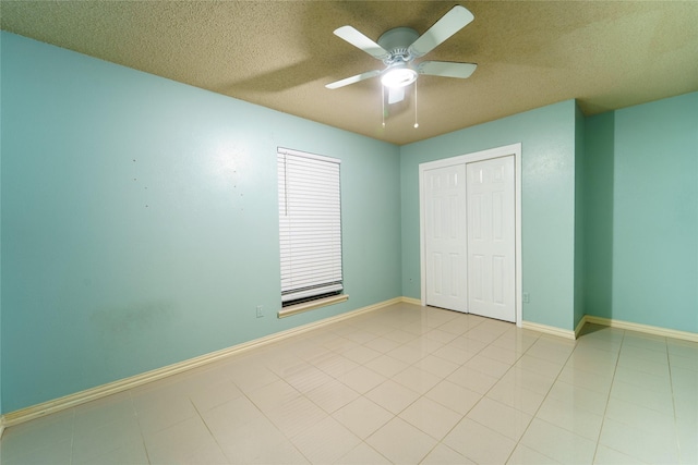 unfurnished bedroom with ceiling fan, light tile patterned floors, a closet, and a textured ceiling