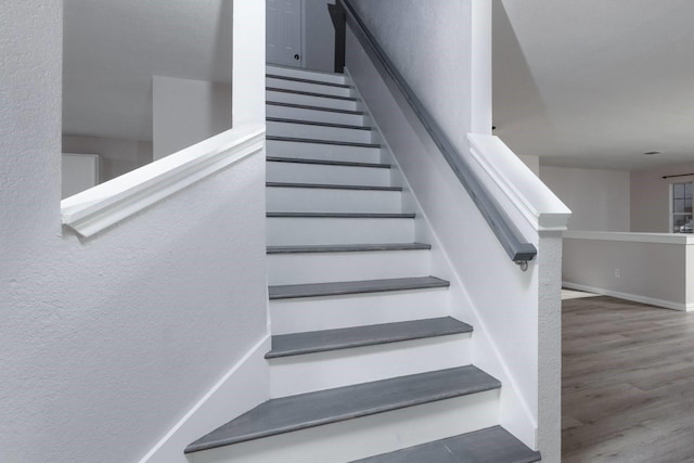 staircase featuring baseboards and wood finished floors