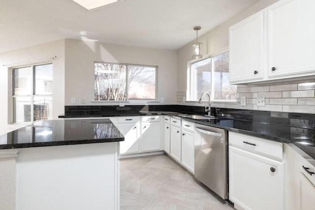 kitchen with dark stone countertops, white cabinetry, a sink, and stainless steel dishwasher