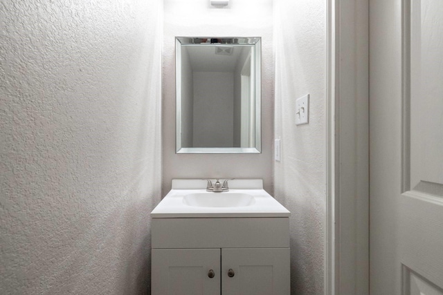 bathroom featuring vanity and a textured wall