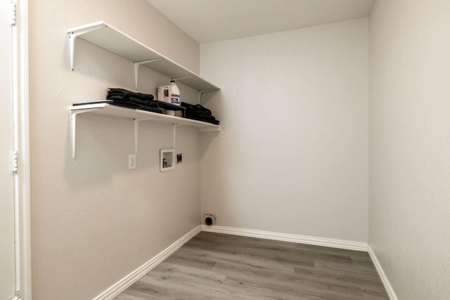 clothes washing area with laundry area, baseboards, washer hookup, and wood finished floors