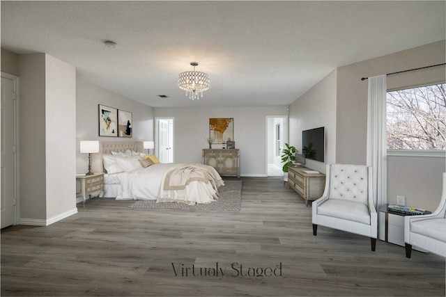 bedroom with a notable chandelier, a textured ceiling, baseboards, and wood finished floors