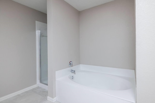 bathroom featuring a stall shower, baseboards, and a bath