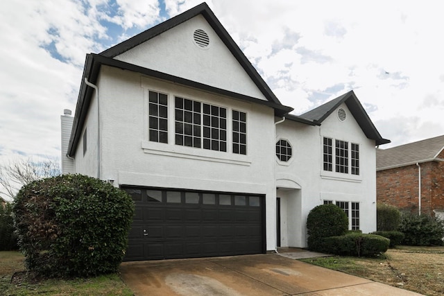 view of front of property with an attached garage, driveway, and stucco siding