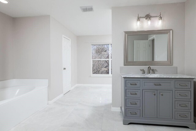 bathroom with visible vents, vanity, baseboards, and a bath