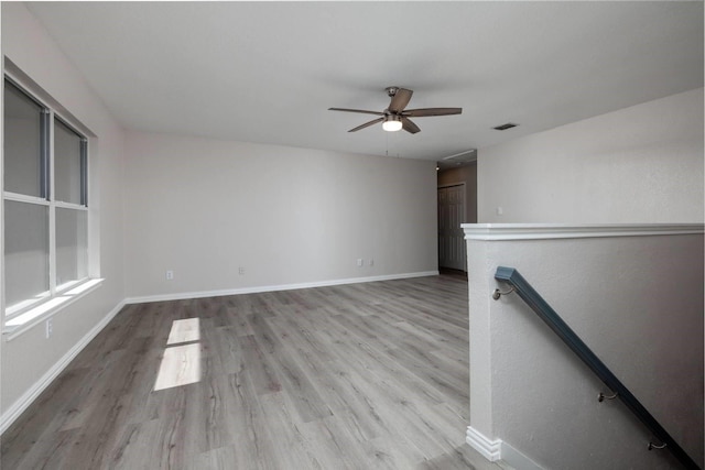 empty room featuring light wood-type flooring, baseboards, visible vents, and ceiling fan