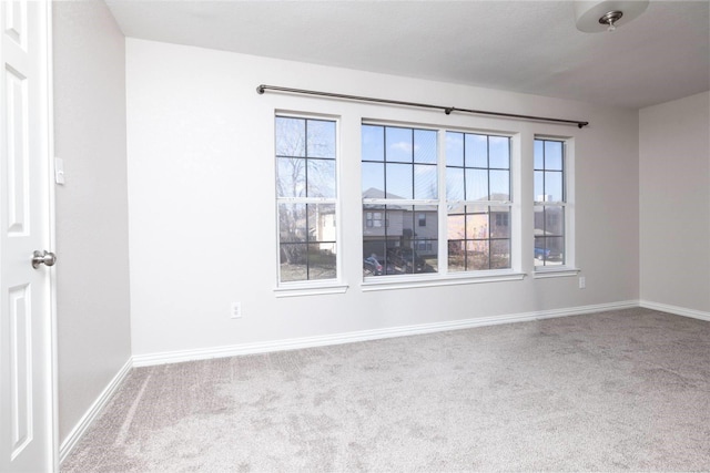 unfurnished room featuring a wealth of natural light, light carpet, and baseboards