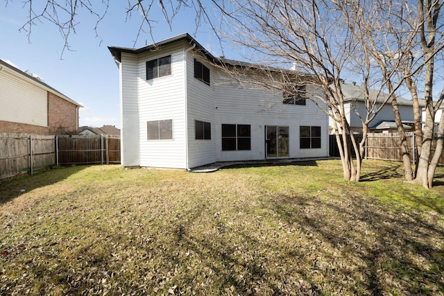 rear view of house with a fenced backyard and a yard