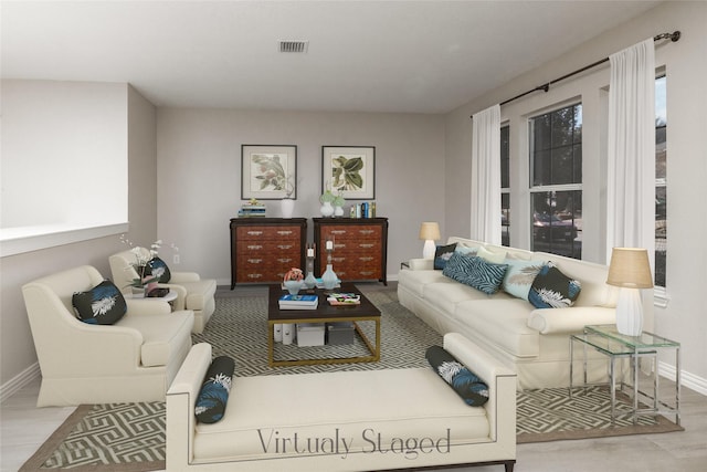 living area with a wealth of natural light, light wood-type flooring, visible vents, and baseboards