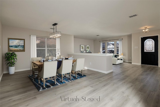 dining space featuring a chandelier, visible vents, baseboards, and wood finished floors