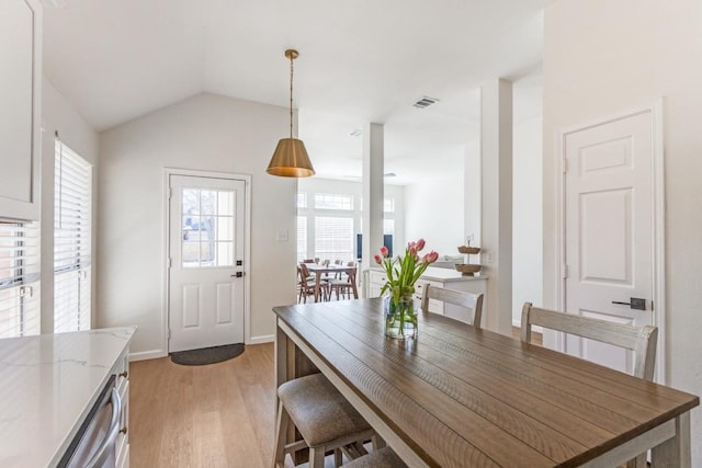 dining space with vaulted ceiling and light wood-type flooring