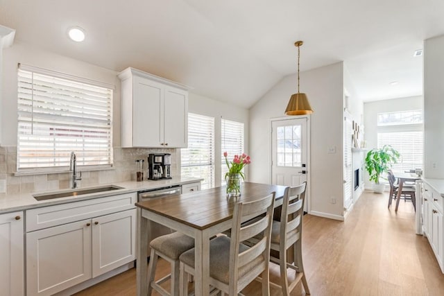 kitchen featuring tasteful backsplash, sink, dishwashing machine, white cabinets, and hanging light fixtures