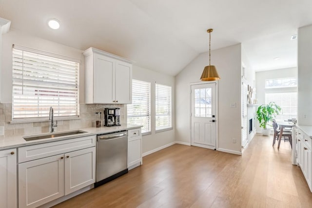 kitchen featuring pendant lighting, sink, dishwasher, white cabinetry, and tasteful backsplash