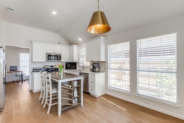 kitchen featuring sink, pendant lighting, stainless steel appliances, decorative backsplash, and white cabinets