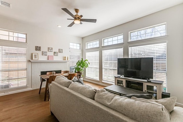 living room with ceiling fan, hardwood / wood-style floors, and a brick fireplace