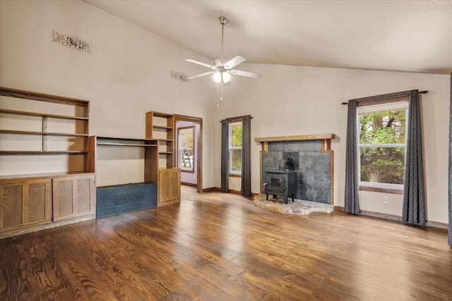 unfurnished living room with hardwood / wood-style floors, ceiling fan, a healthy amount of sunlight, and a wood stove