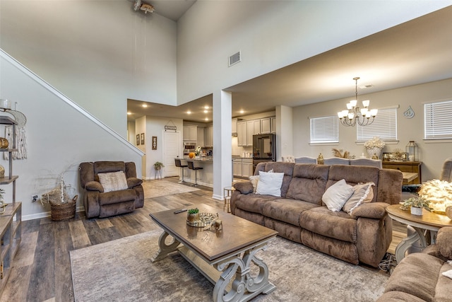 living room featuring wood-type flooring, a chandelier, and a high ceiling