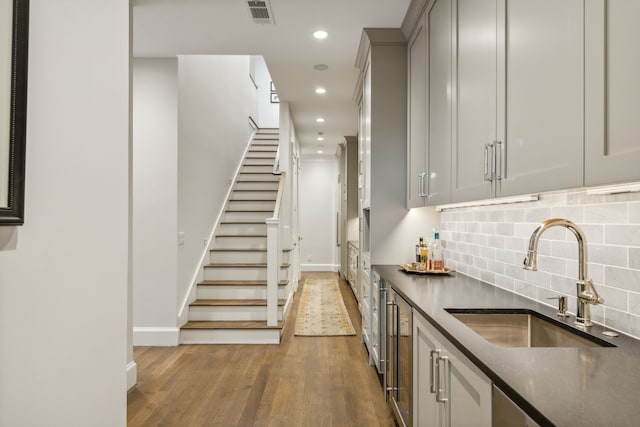 kitchen with hardwood / wood-style flooring, sink, decorative backsplash, and gray cabinetry