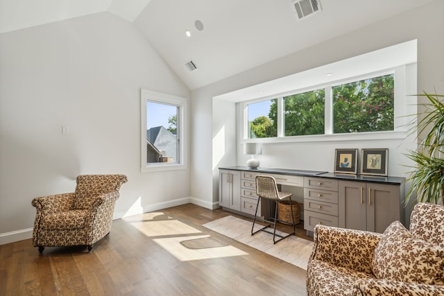 office area with light hardwood / wood-style flooring, built in desk, and high vaulted ceiling