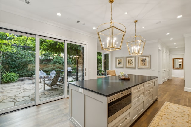 kitchen with white cabinetry, ornamental molding, a healthy amount of sunlight, and decorative light fixtures