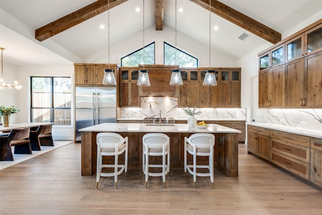 kitchen featuring pendant lighting, built in refrigerator, a center island with sink, and a wealth of natural light