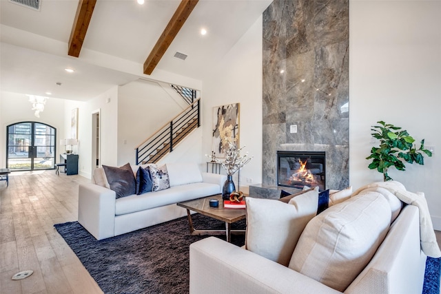 living room with a fireplace, wood-type flooring, beam ceiling, and high vaulted ceiling