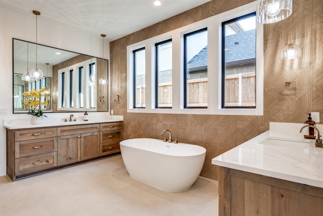 bathroom featuring a tub to relax in, vanity, tile walls, and plenty of natural light