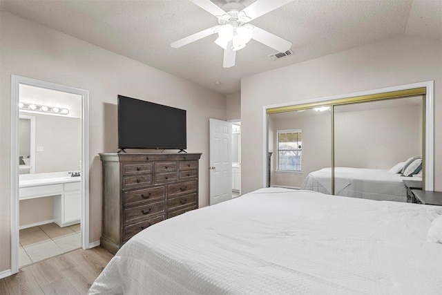 bedroom with connected bathroom, a closet, a textured ceiling, and light wood-type flooring