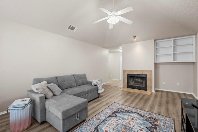 living room featuring hardwood / wood-style flooring, ceiling fan, and a fireplace