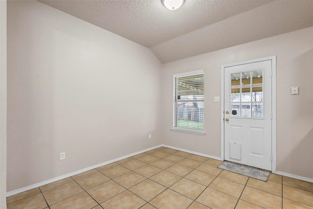 doorway to outside featuring light tile patterned flooring, vaulted ceiling, and a textured ceiling