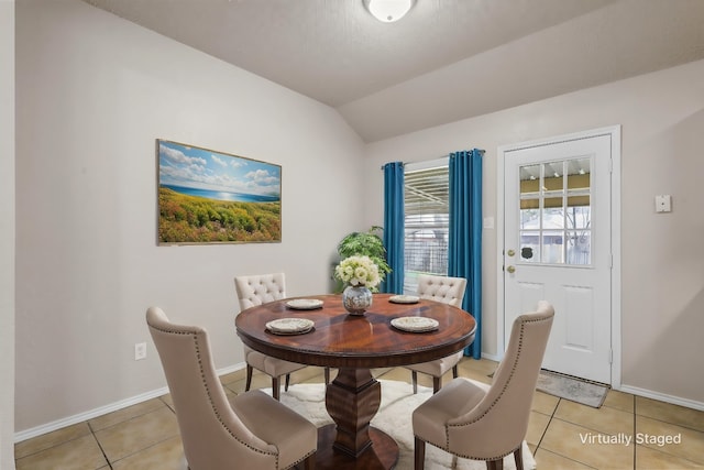 dining area featuring lofted ceiling and light tile patterned floors