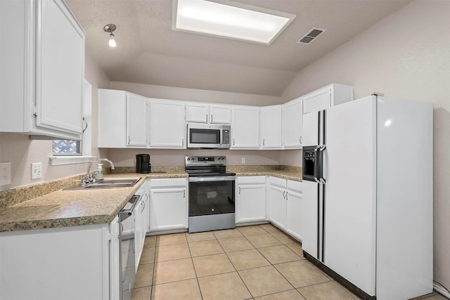 kitchen featuring appliances with stainless steel finishes, white cabinetry, lofted ceiling, sink, and light tile patterned floors