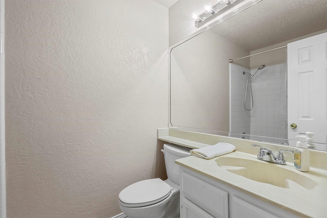 bathroom featuring vanity, toilet, a textured ceiling, and tiled shower