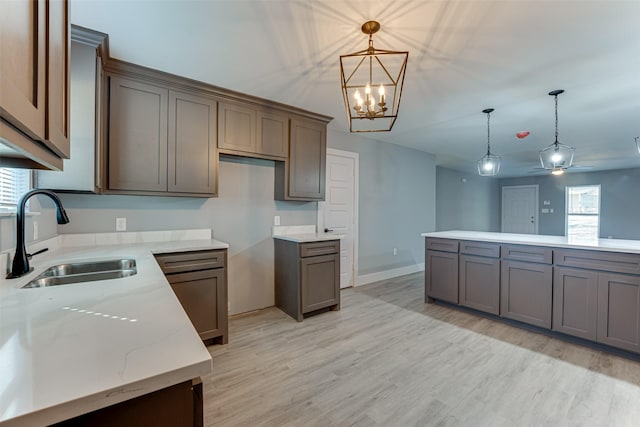 kitchen with sink, decorative light fixtures, light stone countertops, and light hardwood / wood-style floors