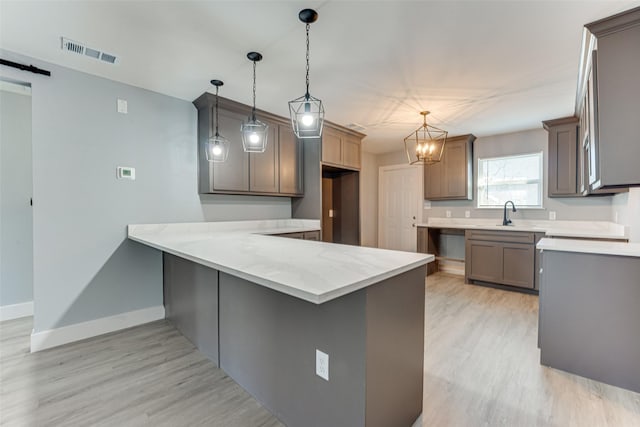 kitchen featuring hanging light fixtures, a barn door, light wood-type flooring, and kitchen peninsula