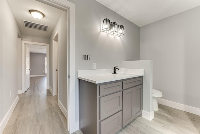 bathroom with hardwood / wood-style flooring, vanity, and toilet