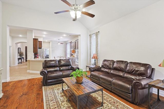 living room with lofted ceiling, sink, ceiling fan, and light hardwood / wood-style flooring